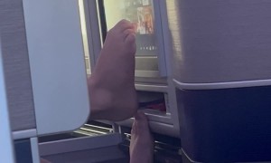 Dude Using Bare Feet to Use Airplane Screen