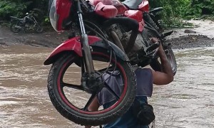 Man Carries His Motorcycle Across River