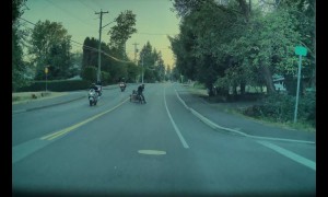 Elderly Bicyclist Pulling Cart Pushed by Passing Motorcyclist