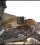 Excavator digs through debris from fallen hotel on earthquake-stricken Indonesia island