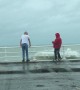 Two grown men play chicken with the tide in Aberystwyth