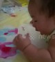 Cute baby tries to eat strawberry pattern on bed sheet