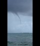 Water spout looms low over cargo ship