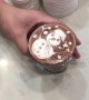 Skilled barista draws intricate snowman on hot chocolate drink