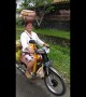 Motorcycling supermum in Bali carries groceries on her head and 4 gas cylinders