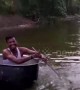 Man rows over water in cooking pot boat with spatula paddle
