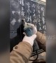 Skilful man shows off calligraphy on stone slab using a power grinder