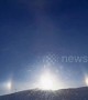 Sundog over snowy hilltop in Minnesota casts brilliant glare during blizzard