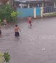 Filipino children make the most of the bad weather by playing in flooded street