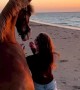 Horse and caretaker enjoy watching the sunset at the beach