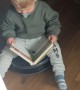 Toddler Reads a Book While Riding Robot Vacuum