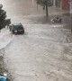 Car Drives Through Flooded Street in Spain