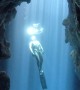 Cave View of a Free Diver Swimming Through Bubble Rings